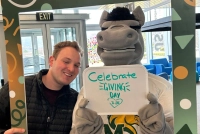 student and mascot holding a sign saying celebrate giving day